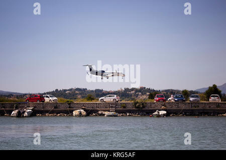 Blick auf kleine private Jet (Flugzeug) Landung auf Korfu (Kerkyra) Flughafen. Autos und das Mittelmeer sind auch in der Szene. Stockfoto