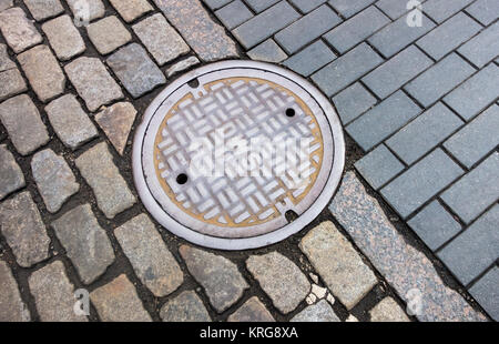 Eine Mischung aus Kopfsteinpflaster Typen um einen Abwasserkanal in Lower Manhattan. Stockfoto