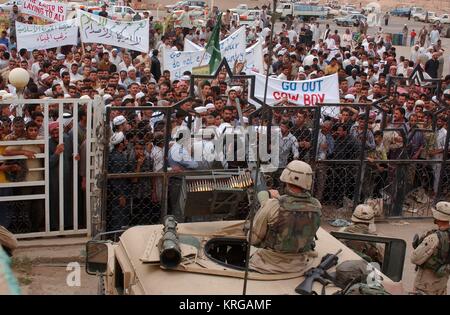 Us-Soldaten von oben ansehen Tank guard Beiträge als irakische Zivilisten Protest U.S. Army Präsenz und Nachfrage in den USA verlässt Irak nach der Befreiung am 27. April 2003 in Samarra, Irak. Stockfoto
