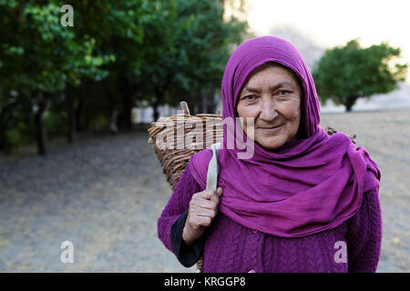 Ein balti Frau tragen bunte Schal und einen gestrickten Korb auf dem Rücken, Turtuk, Nubra Valley, Ladakh, Jammu und Kaschmir, Indien. Stockfoto