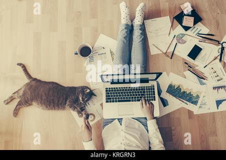 Entspannt von zu Hause aus arbeiten: Mädchen auf einer Etage arbeiten durch Ihre Katze unterstützt Stockfoto