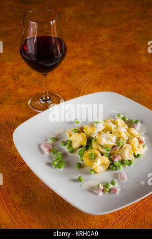 Tortellini mit Sahne Schinken Erbsen und Rotwein Stockfoto