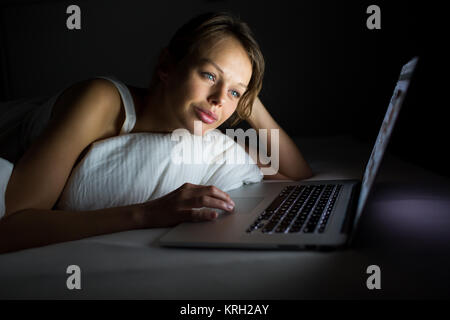 Hübsche, junge Frau mit ihren Laptop im Bett Stockfoto