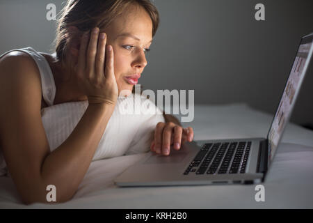 Hübsche, junge Frau mit ihren Laptop im Bett Stockfoto