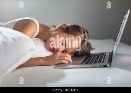 Hübsche junge Frau schlief, während auf Ihrem Laptop im Bett arbeiten Stockfoto