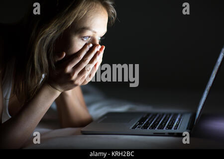Hübsche junge Frau, die gerade etwas schrecklich/sad auf ihrem Laptop im Bett Stockfoto