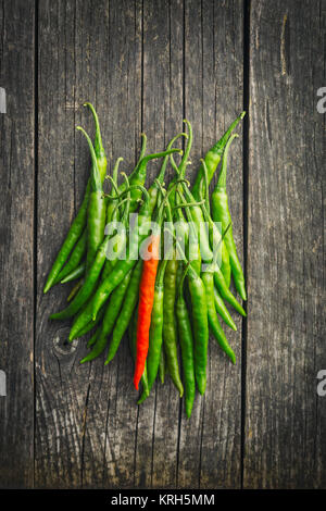 Grüne Chilischoten und eine rote Chili. Stockfoto