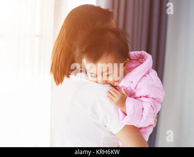 Schreiendes Baby in der Hand der Mutter am Fenster Stockfoto