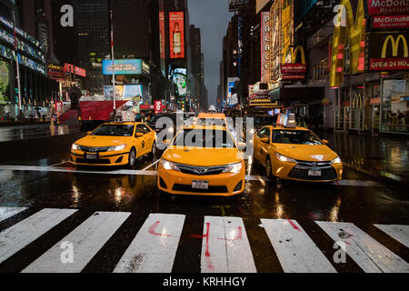 New York Medaillon Gelbe Taxis Line up an der Kreuzung an einem regnerischen Abend in der Zeit von Square, New York City, Nordamerika Stockfoto