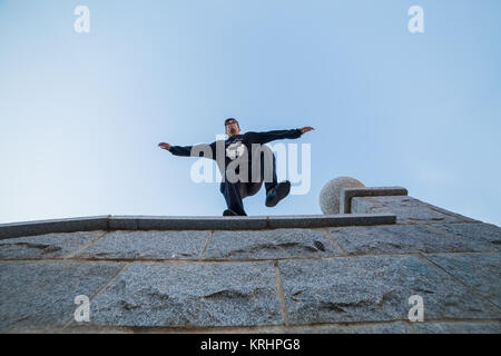 Junger Mann dabei eindrucksvolle parkour Sprung von einer Wand auf den Boden. Stockfoto