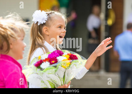 Erste-Grader an der Schule am 1. September in Gruß winken seiner Freundin Stockfoto