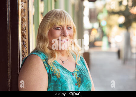 Transgender blonde Dame lächelnd außerhalb Stockfoto