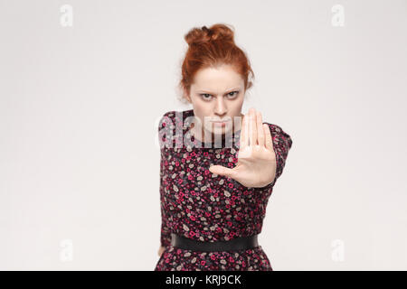 Isolierte studio Shot auf grauem Hintergrund. Rothaarige Frau mit schlechten Haltung, stop Geste mit ihrer Handfläche nach Außen, nein zu sagen, mit dem Ausdruck der Ablehnung oder re Stockfoto