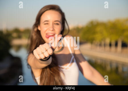 Glücklich aussehende junge Frau im Park an einem sonnigen Tag und deutete mit dem Daumen nach oben. Stockfoto