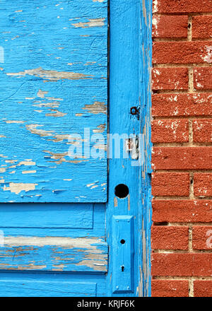 Teil einer Peeling blaue Holztür mit fehlenden Türknauf steht im Gegensatz gegen die Red brick wall auf der Route 66 in Stroud, Oklahoma. Stockfoto