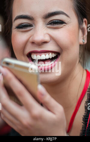 Mädchen im Dirndl Kleid Spaß haben, während sie ihr Mobiltelefon auf dem Oktoberfest Stockfoto