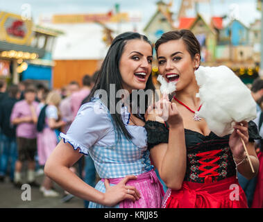 Zwei junge Frauen im Dirndl Kleid oder Tracht, lachend mit Baumwolle Zuckerwatte auf dem Oktoberfest Stockfoto