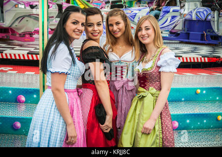 Attraktive und freudige woamn an deutschen Oktoberfest mit traditionellen Dirndl und joyride im Hintergrund. Stockfoto