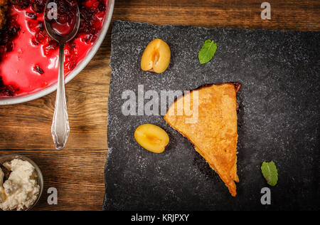 Hausgemachte gebackene Dessert plum Schuster mit Schlagsahne auf Holz Tisch Stockfoto