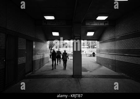 Durchgang zu Sport oval mit Schattenrissen von Personen, zu Fuß. Flur mit gemauerten Wänden und Decke zu einer Sportarena. Schwarz-weiß Foto o Stockfoto