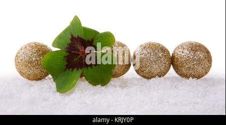 Weihnachtsdekoration mit Schnee auf weißem Hintergrund. Lucky Symbole: Kleeblatt und Bälle. Grüne Kleeblatt und Dekoration. Stockfoto