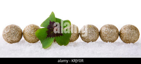 Weihnachtsdekoration mit Schnee auf weißem Hintergrund. Lucky Symbole: Kleeblatt und Bälle. Grüne Kleeblatt und Dekoration. Stockfoto