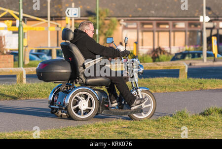 Mann, ein 3 Rad elektrische deaktiviert Mobilität scooter in Großbritannien. Stockfoto