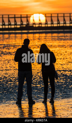 Silhouette von ein paar den Sonnenuntergang am Strand im Winter in England, Großbritannien. Porträt. Stockfoto