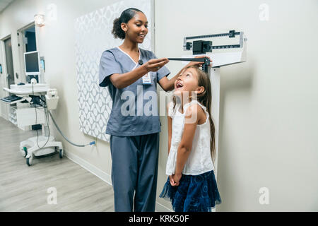 Krankenschwester Messhöhe von Mädchen Stockfoto