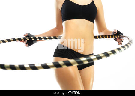 Flacher Bauch und Gesäß, die Frau, die Züge mit Rad hula Hop. Stockfoto