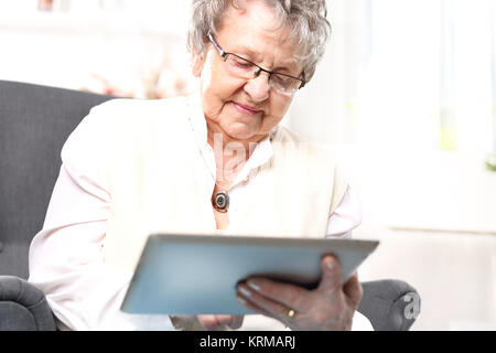 Oma und dem Computer. Eine ältere Frau mit einem Tablet. pensionierte, Unterhaltung im Internet Stockfoto