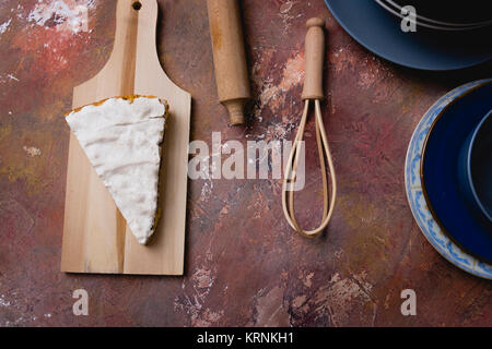 Stück Schokolade Kuchen mit Baiser auf der Oberfläche auf einer hölzernen Schneidebrett platziert Stockfoto