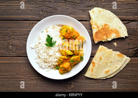 Chicken Curry mit Reis auf Holz- Hintergrund. Ansicht von oben, flach Stockfoto