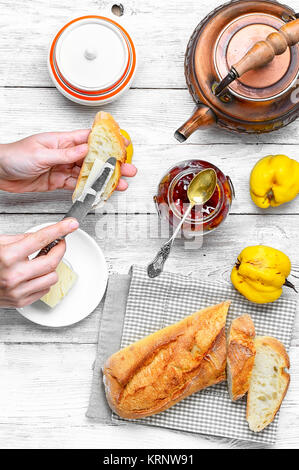 Hände, die Vorbereitung für das Frühstück mit Brot, Butter und Marmelade für Tee Stockfoto