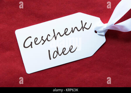 Deutsche Text Geschenk Idee bedeutet Geschenk Idee. Eine White Label auf einem Roten strukturierten Hintergrund. Tag mit Band. Stockfoto