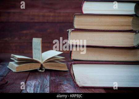 Stapel alter Bücher auf braunem Holz- Oberfläche in der Nähe der offenen Buch Stockfoto