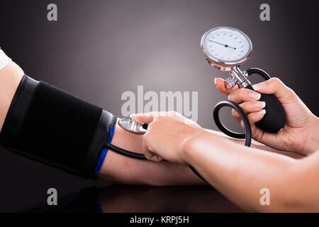 Arzt Kontrolle Blutdruck des Patienten Stockfoto