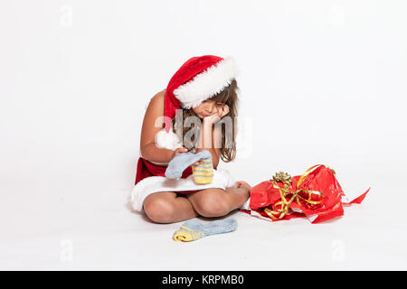 Trauriges Mädchen in Santa Claus Kostüm mit ungeeigneten Geschenk Stockfoto