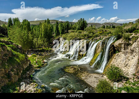 Wasserfälle in einer grünen Umgebung unter blauem Himmel mit flauschigen weissen Wolken Stockfoto