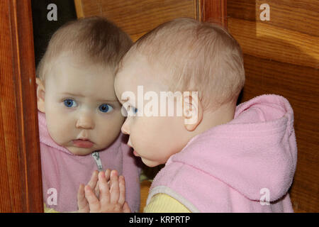 Baby schaut sich vor Spiegel Stockfoto