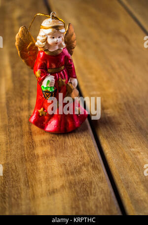Klassische Engel Christbaumschmuck Figur mit einem roten Kleid auf Holz Textur Stockfoto