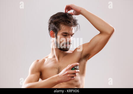 Junger Mann wird auf seine Achselhöhle Antitranspirant angewendet. Stockfoto