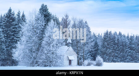Weihnachten serene Panoramablick auf die Landschaft winzige Kapelle bei Schnee gefroren Wald Stockfoto