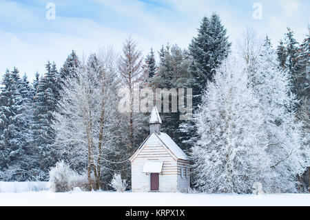 Kleine hölzerne Kapelle auf verschneite frosty Glade bei Schnee gefroren Wald Stockfoto