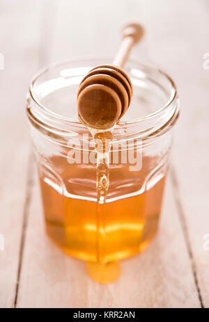 Golden klar Honig im Glas mit Löffel und Nieselregen Stockfoto