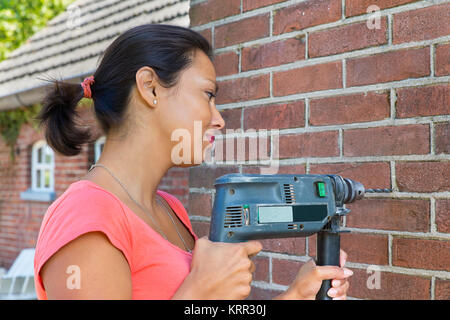 Junge kolumbianische Frau mit Bohrmaschine brick wall Stockfoto