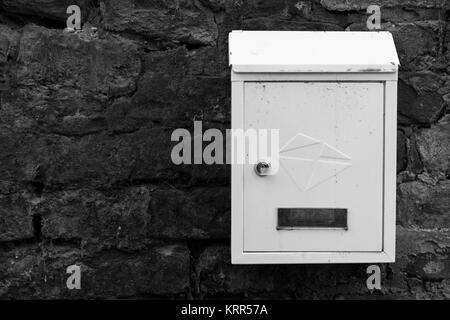 White Metal Mailbox auf einem Red brick wall. Alte Mauer. Mailbox mit Staub und Schmutz. Stockfoto