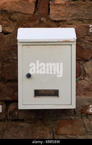White Metal Mailbox auf einem Red brick wall. Alte Mauer. Mailbox mit Staub und Schmutz. Stockfoto