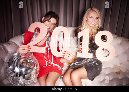 Frauen mit der Nummer des neuen Jahres sitzt auf einem Sofa in der Nacht Club Stockfoto