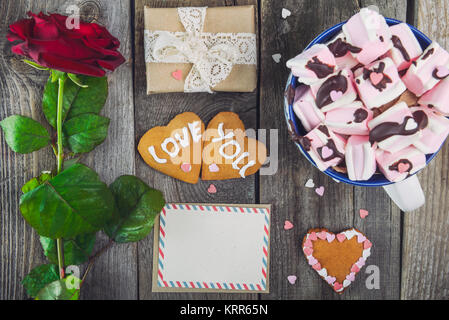 Festliche Komposition mit hausgemachten Plätzchen in der Form von Herzen mit Liebe sie Schriftzüge, Grußkarte, Rose, Geschenkbox und Tasse Kakao. Geschenk für Liebhaber auf Stockfoto